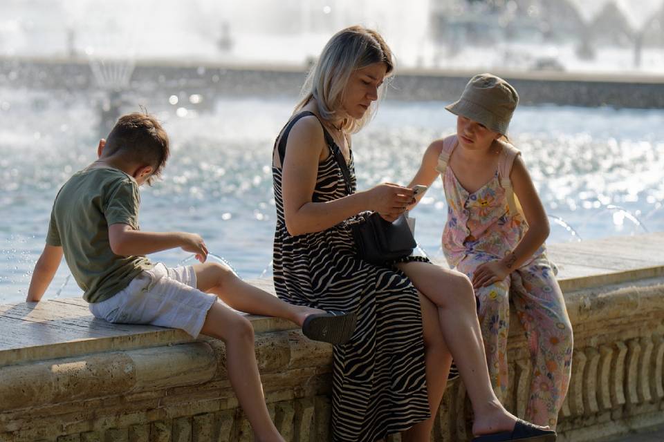Mutter sitzt mit Ihren Kindern an einem Fluss
